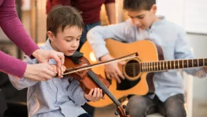 Group music lesson with violin and guitar students learning together with instructor guidance in classroom setting