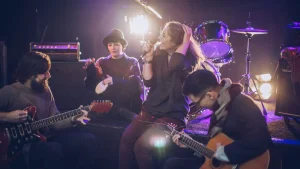 Modern band ensemble performing live with guitars, vocals, and drums in atmospheric stage lighting from Legato Music School, Kota Kinabalu