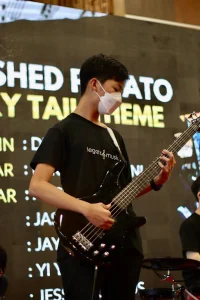 Young bassist performing live electric bass guitar on stage wearing official Legato Music t-shirt and face mask