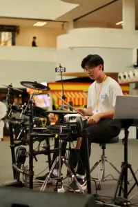Student drummer playing electronic drums during practice session with professional drum setup
